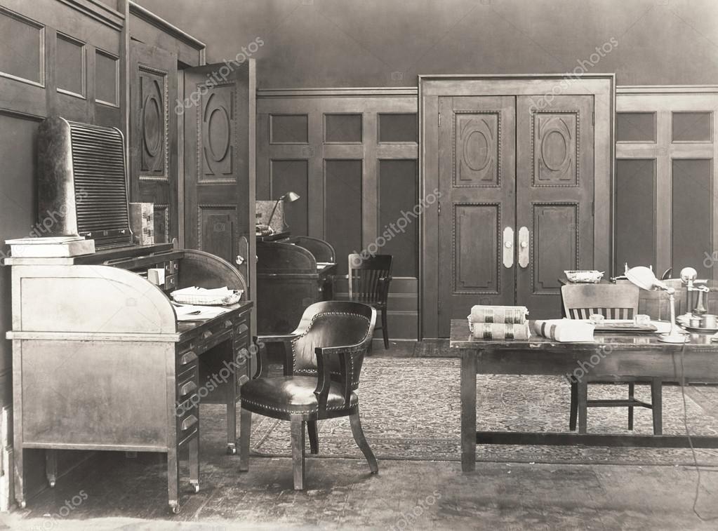 foto 3_imagen del despacho vacío y elegante que tiene el escritorio de persiana a la izquierda, una silla de cuero en el centro y grandes puertas dobles al fondo